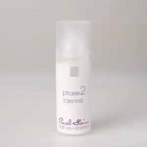 Eine kleine, zylindrische, weiße Flasche mit mattiertem Deckel und der Aufschrift „intervall Avocadoöl parfümfrei 50ml Phase 2“ in violetter Schrift. Der Produktaufdruck auf der Unterseite lautet „Ruel Heim nature + science“. Die Flasche steht auf einem schlichten, hellgrauen Hintergrund.